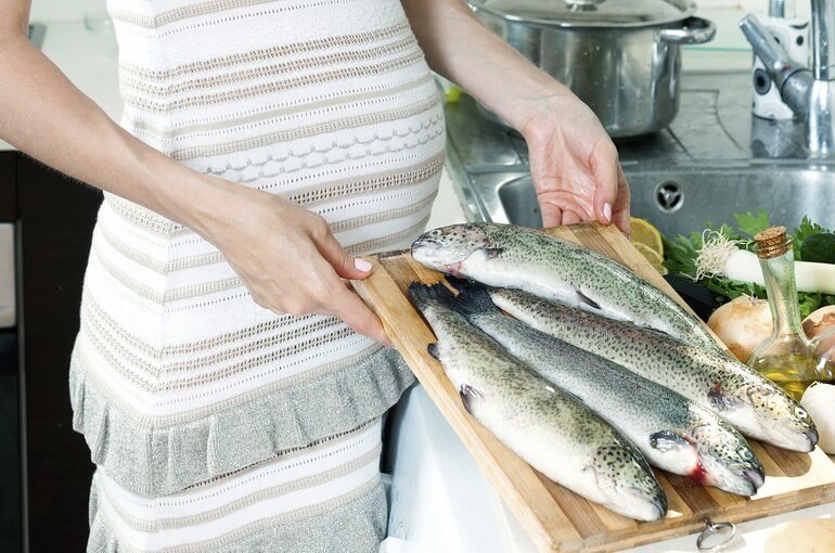 Беременная женщина разделывает рыбу